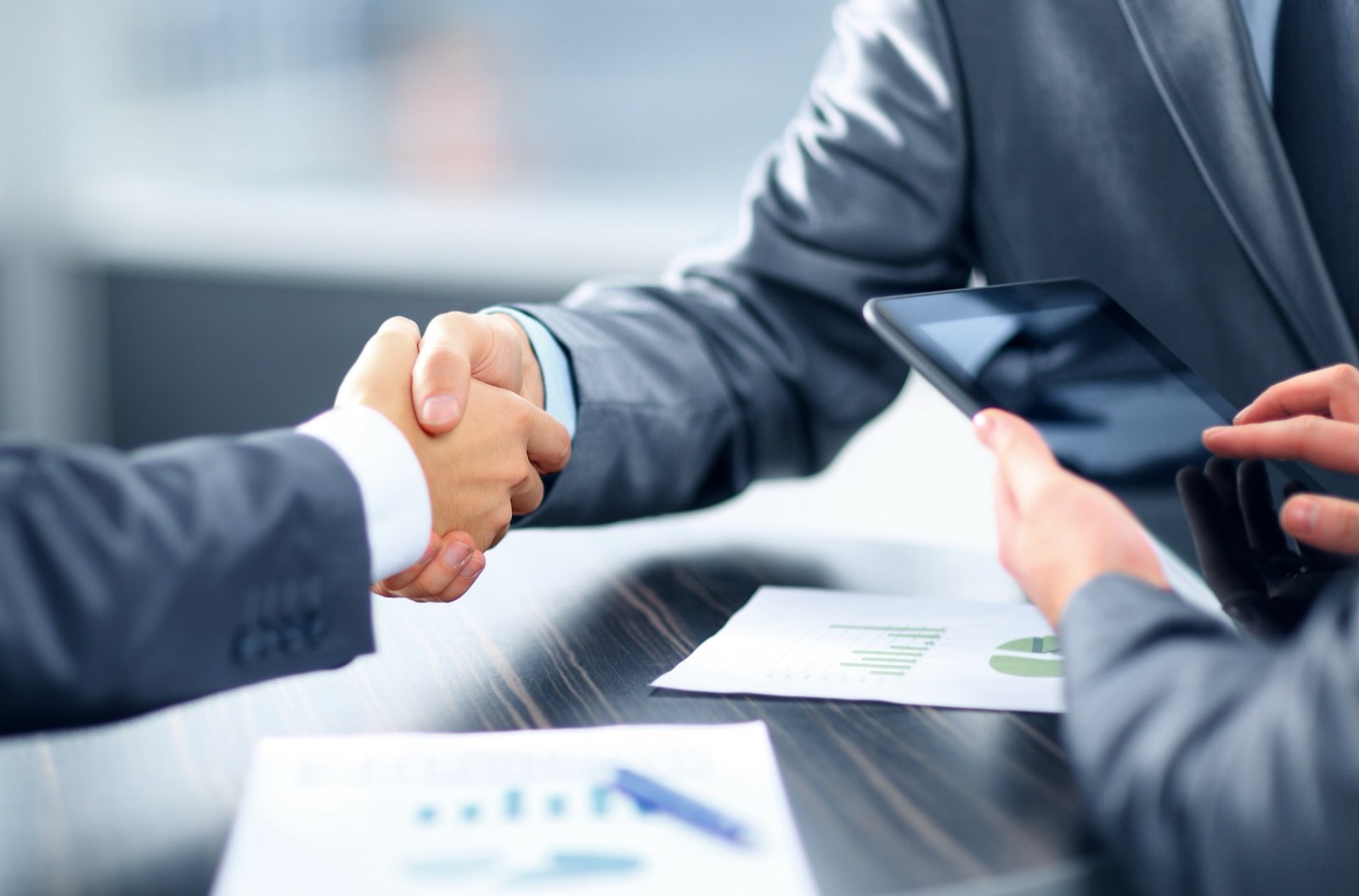 Two business people shaking hands over a meeting table